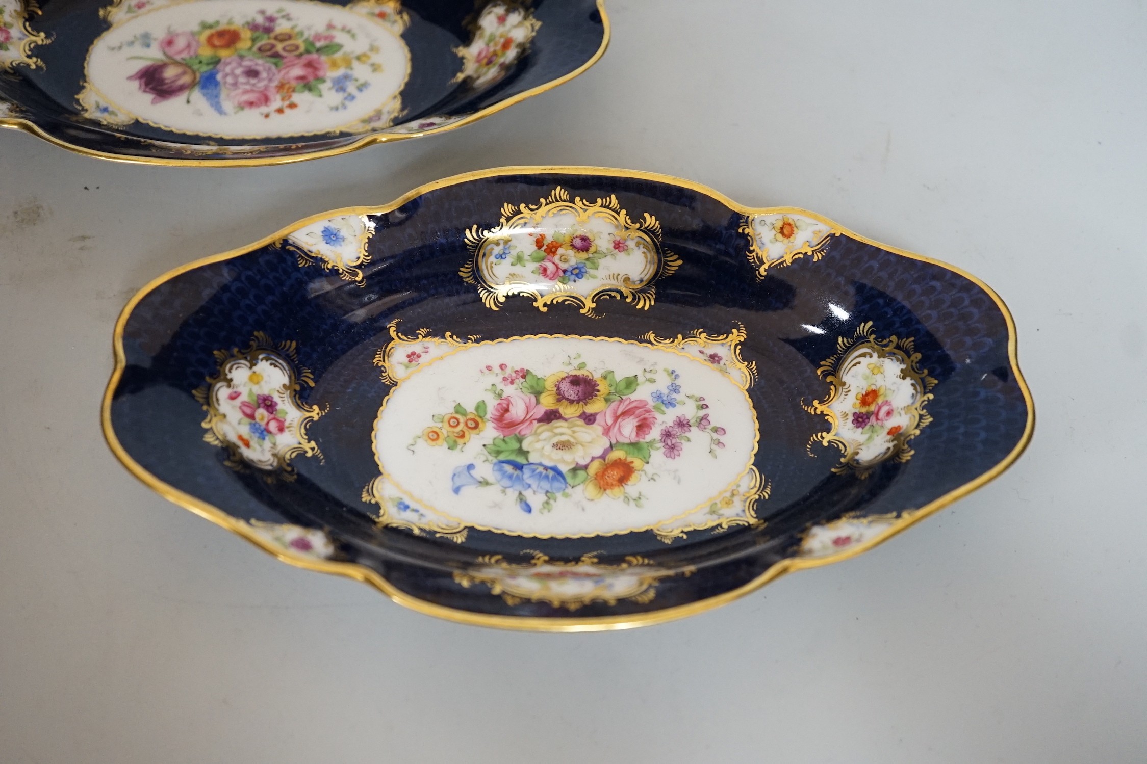 A pair of Royal Worcester blue ground floral painted dishes by E Phillips, signed date code for 1894, length 21cm
